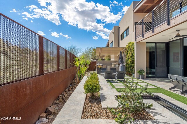 view of yard with a balcony, ceiling fan, and a patio area