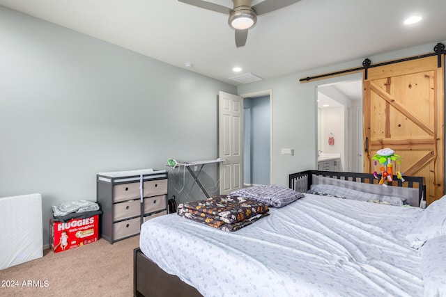 carpeted bedroom featuring a barn door and ceiling fan