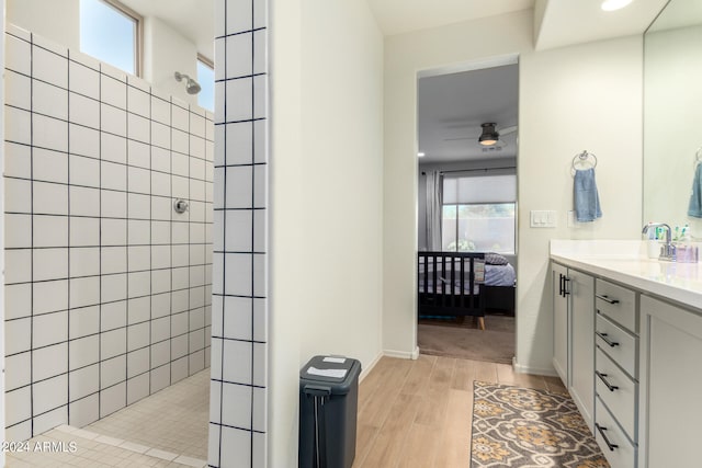 bathroom with vanity, a tile shower, wood-type flooring, and ceiling fan