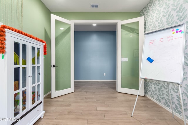 corridor featuring light hardwood / wood-style floors and french doors