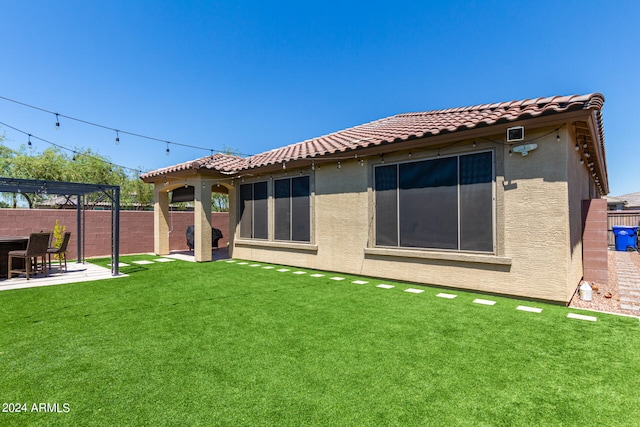 back of property with a patio area, a yard, and a pergola