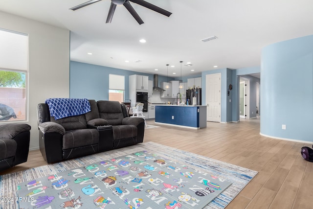 living room with sink, light wood-type flooring, and ceiling fan