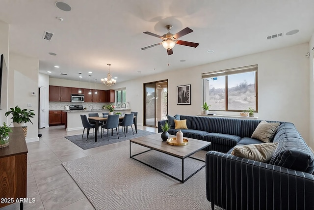 tiled living room featuring a healthy amount of sunlight and ceiling fan with notable chandelier