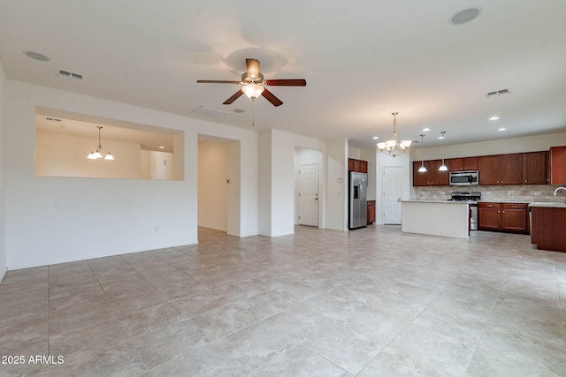 kitchen with stainless steel appliances, tasteful backsplash, hanging light fixtures, and ceiling fan with notable chandelier