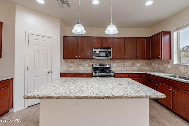 kitchen with light stone counters, decorative light fixtures, a center island, and appliances with stainless steel finishes