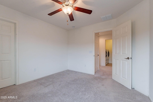 carpeted spare room with washing machine and dryer and ceiling fan