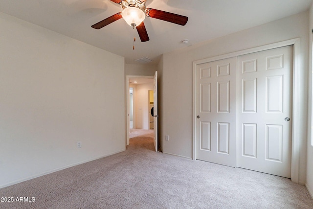 unfurnished bedroom with ceiling fan, light colored carpet, and a closet