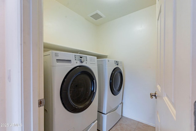 clothes washing area with light tile patterned floors and washer and clothes dryer