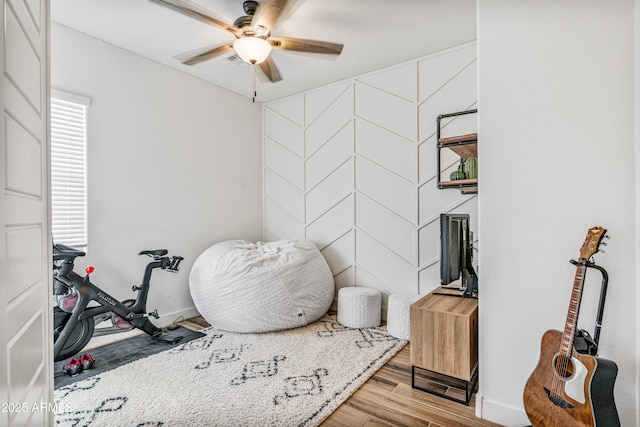 interior space featuring baseboards, a ceiling fan, and wood finished floors