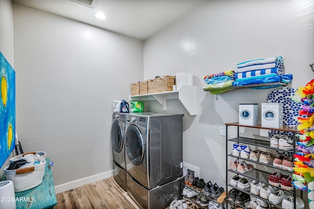 washroom featuring laundry area, wood finished floors, baseboards, and washing machine and clothes dryer