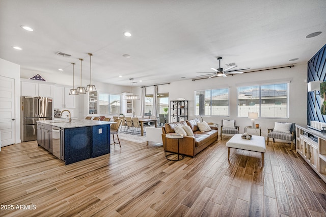 living room with recessed lighting, visible vents, ceiling fan, and light wood finished floors