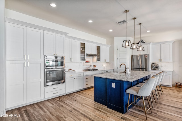 kitchen with a kitchen bar, light wood-style flooring, appliances with stainless steel finishes, and a sink