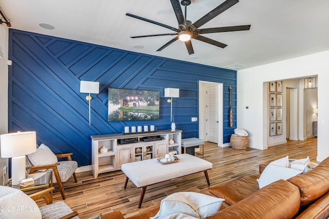 living room with ceiling fan, baseboards, and wood finished floors