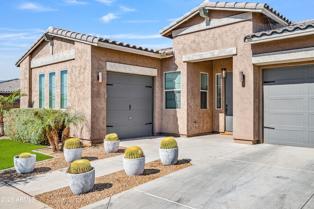 view of front facade with stucco siding, a garage, concrete driveway, and a tile roof