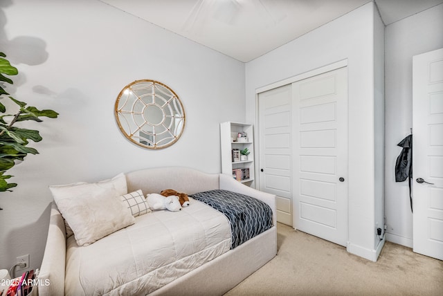 carpeted bedroom with a closet and baseboards