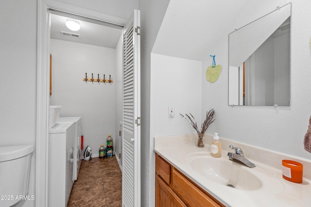bathroom with separate washer and dryer, vanity, and toilet