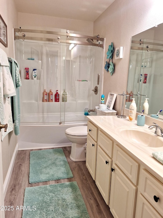 full bathroom featuring shower / bath combination with glass door, hardwood / wood-style floors, vanity, and toilet