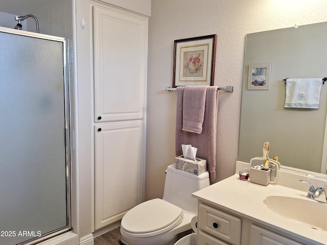 bathroom with vanity, toilet, a shower with door, and wood-type flooring