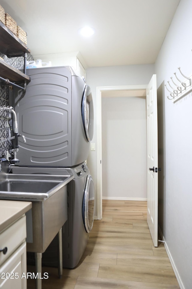 laundry area featuring light wood-type flooring and stacked washer / drying machine