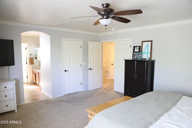 carpeted bedroom with crown molding, ceiling fan, and ensuite bath