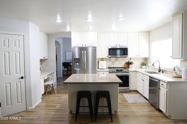 kitchen featuring a center island, sink, appliances with stainless steel finishes, white cabinets, and a kitchen breakfast bar