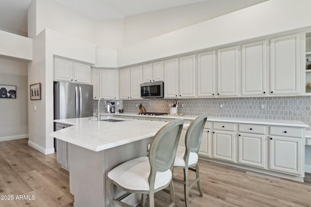 4960 E Dale Ln, Cave Creek, AZ 85331 - kitchen with stainless steel appliances, a sink, light wood finished floors, backsplash, and a towering ceiling