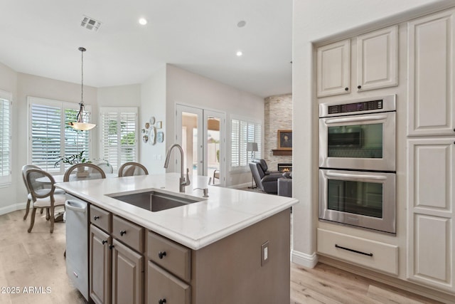 4960 E Dale Ln, Cave Creek, AZ 85331 - kitchen with appliances with stainless steel finishes, a sink, light wood-style flooring, an island with sink, and baseboards