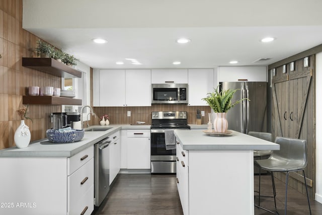 kitchen featuring white cabinets, a kitchen island, stainless steel appliances, and a sink