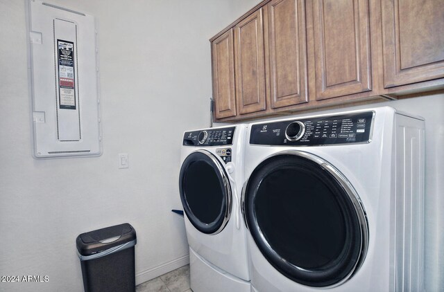 washroom with cabinets, light tile patterned floors, electric panel, and washer and dryer