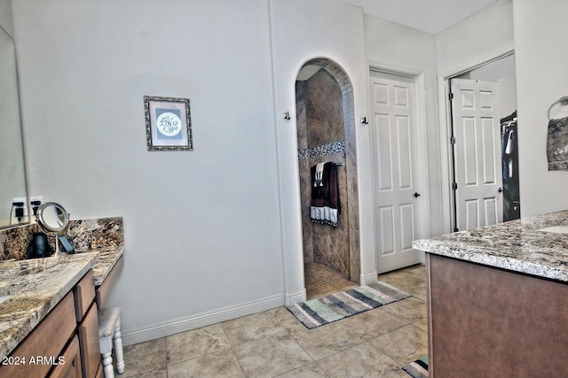 bathroom with tile patterned floors, a shower, and vanity