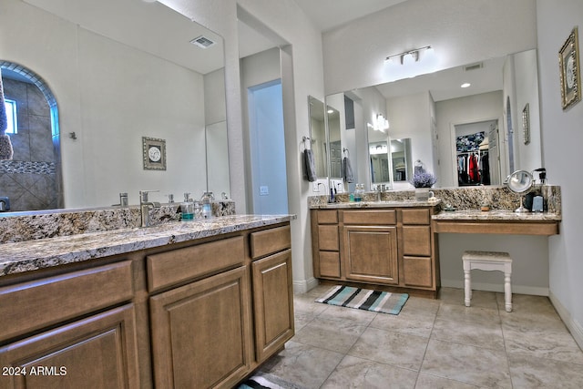 bathroom with a tile shower, vanity, and tile patterned floors