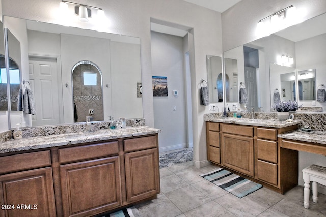 bathroom with tile patterned flooring, a tile shower, and vanity