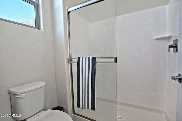 bathroom with toilet and a shower with shower door