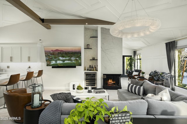 living room featuring vaulted ceiling with beams, wine cooler, and a high end fireplace