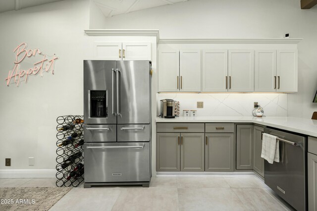 kitchen featuring light tile patterned floors, gray cabinetry, backsplash, stainless steel appliances, and white cabinets