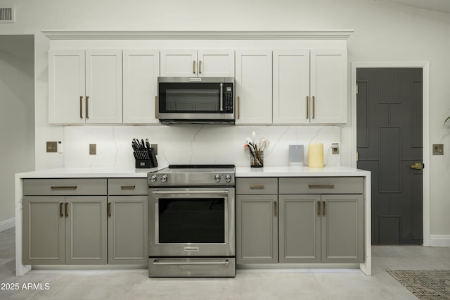 kitchen featuring backsplash, white cabinets, appliances with stainless steel finishes, and gray cabinetry