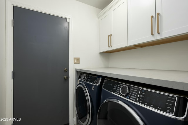 clothes washing area with washer and clothes dryer and cabinets