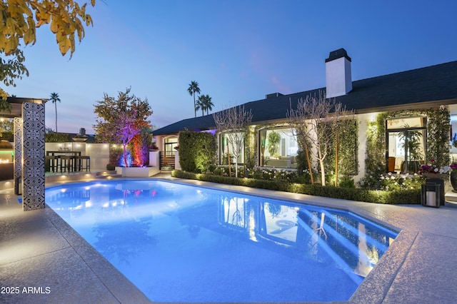 pool at dusk featuring a patio