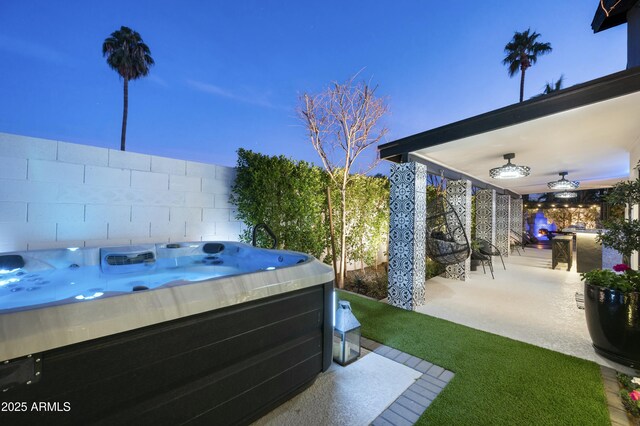 yard at dusk with a hot tub, a patio, and ceiling fan