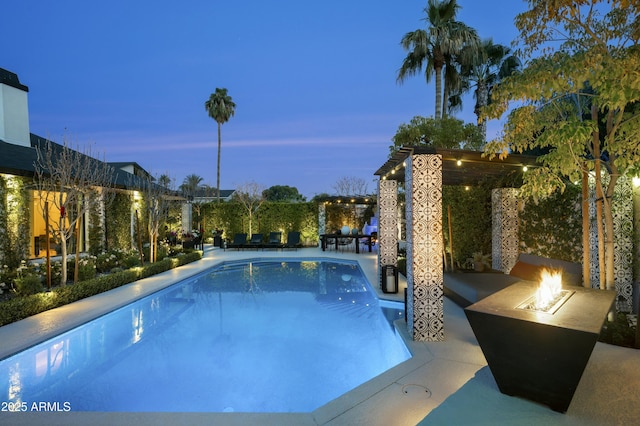 pool at dusk featuring a patio area and an outdoor fire pit