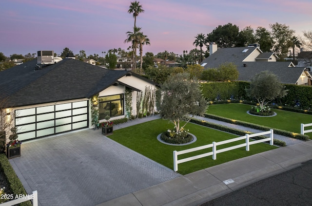 view of front of house with a garage, central AC, and a lawn