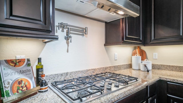 kitchen featuring stainless steel gas stovetop, light stone counters, and exhaust hood