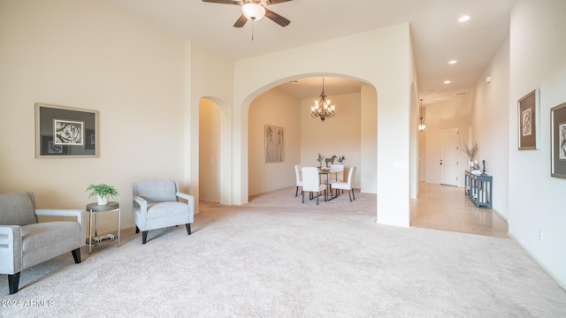 sitting room with light carpet and ceiling fan with notable chandelier