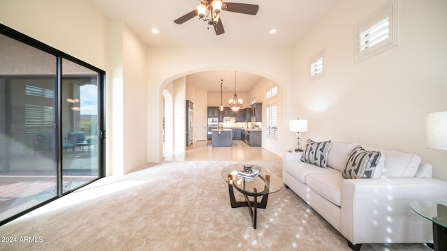 carpeted living room featuring ceiling fan with notable chandelier