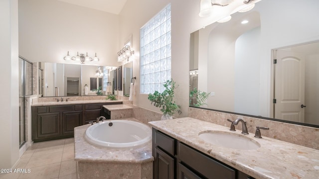 bathroom with tile patterned flooring, vanity, and tiled bath