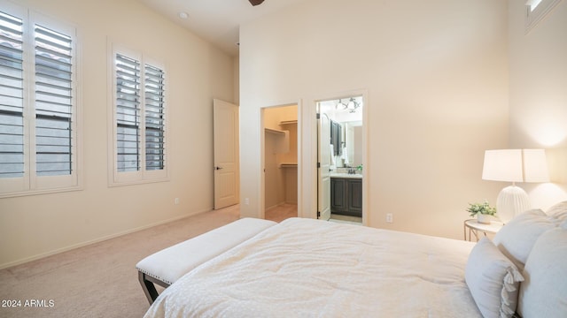 bedroom featuring light carpet, sink, ensuite bath, a spacious closet, and a closet