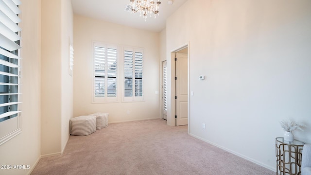 carpeted empty room with a notable chandelier