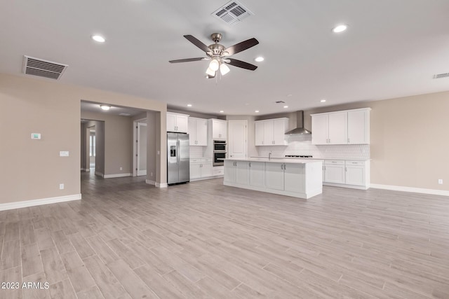 kitchen featuring ceiling fan, white cabinetry, wall chimney exhaust hood, stainless steel appliances, and light hardwood / wood-style floors