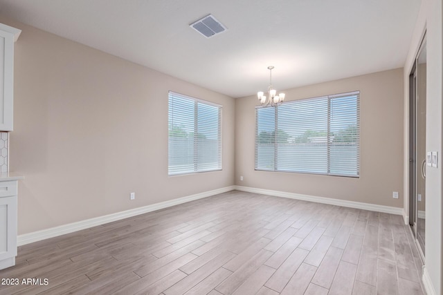 unfurnished dining area featuring a chandelier and light hardwood / wood-style floors