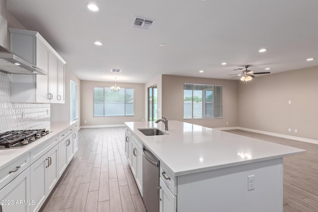 kitchen with plenty of natural light, a kitchen island with sink, wall chimney exhaust hood, and sink